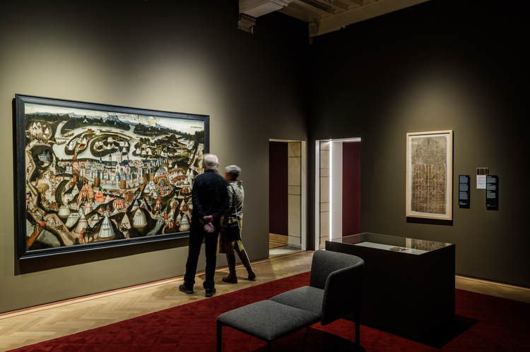 Twee mensen staan voor een groot schilderij in een museumzaal.