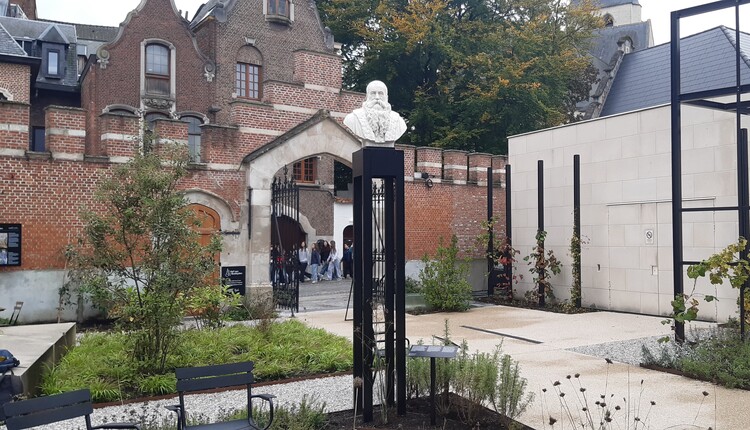 Een wit marmer borstbeeld staat op een hoge metalen sokkel in de museumtuin.